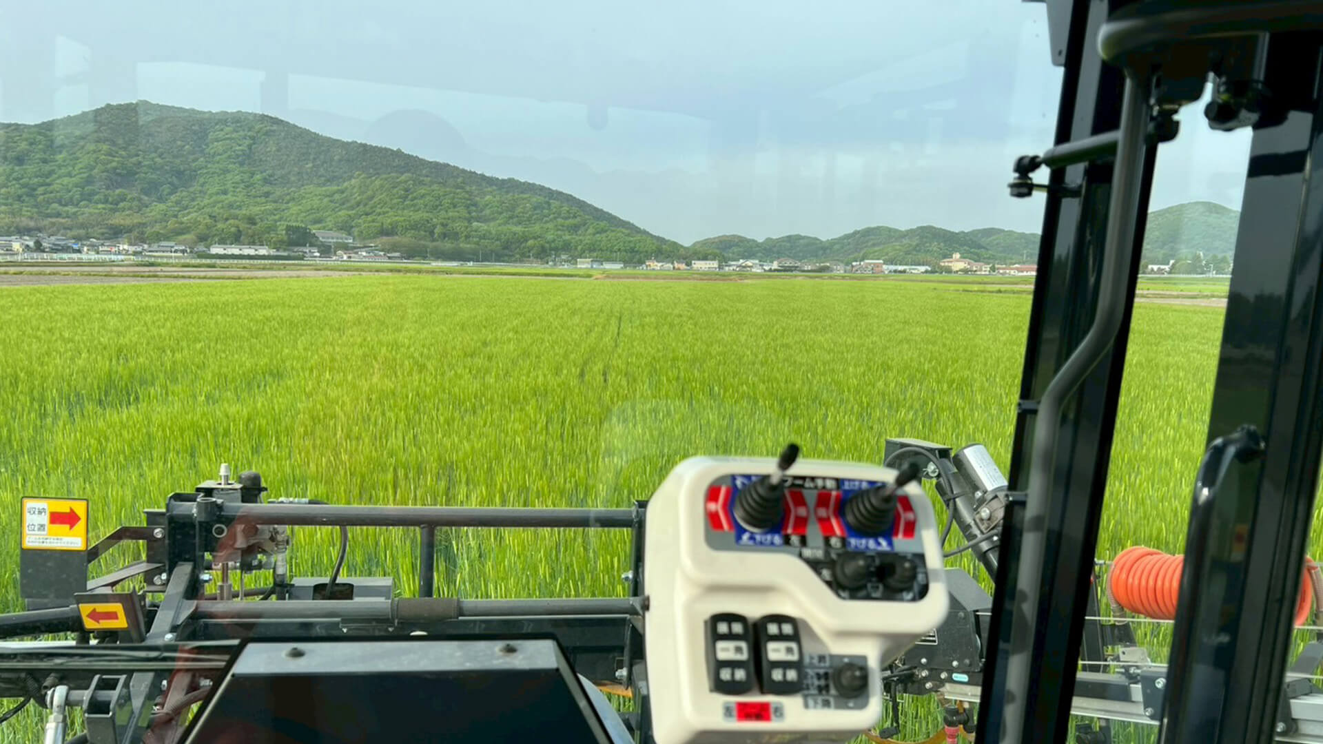 トラクターの運転席から見た、青い水田
